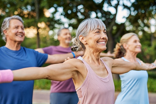 Happy senior group doing yoga together in the park.