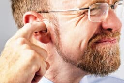 Man touches ear in pain