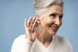Happy senior woman showing off her new hearing aid