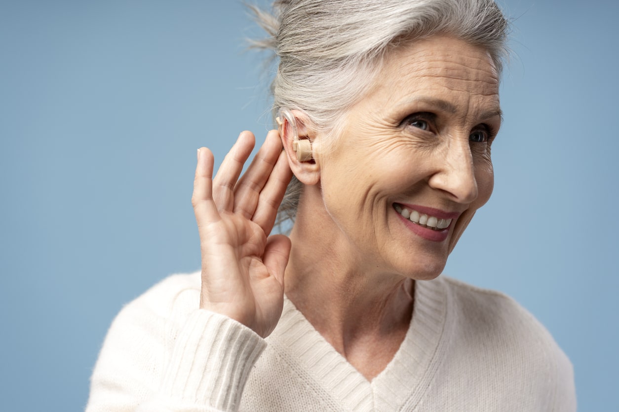 Happy senior woman showing off her new hearing aid.