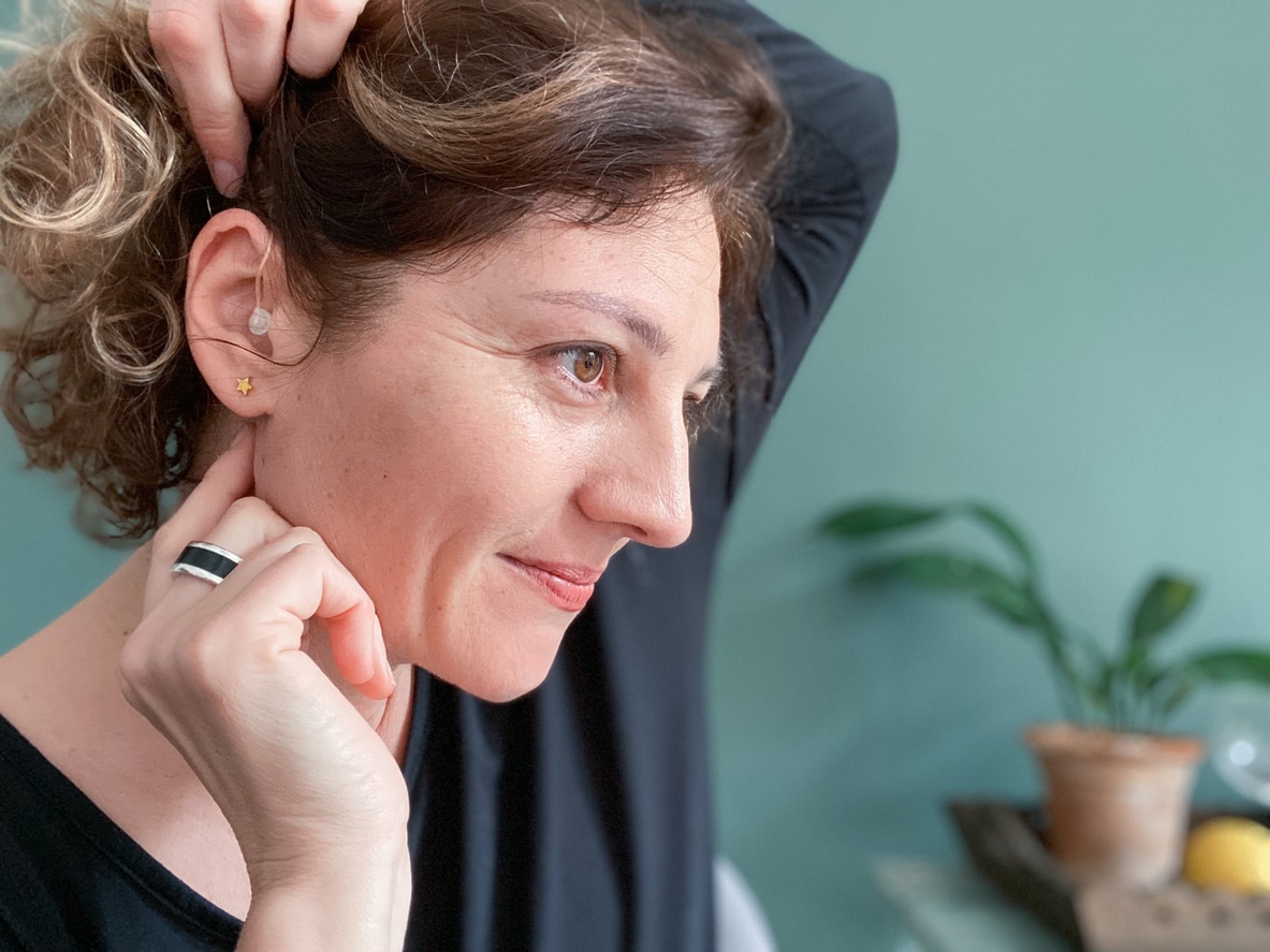 Smiling woman showing her correctly placed hearing aid.