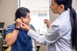 Man at a hearing aid service appointment taking out his hearing aid to show the doctor