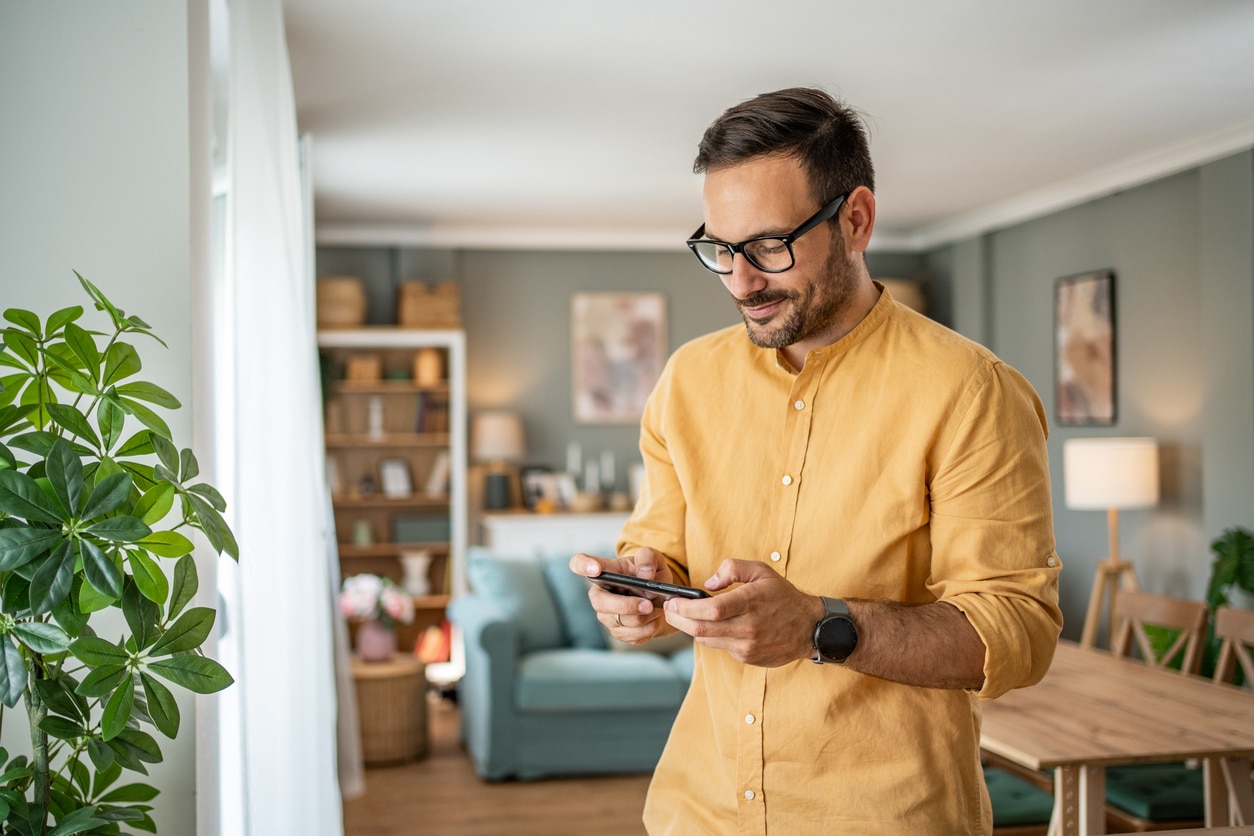Portrait of cheerful man using smartphone at home.