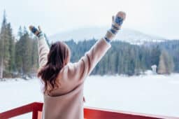 Woman stretching her arms looking at the snowy wilderness.