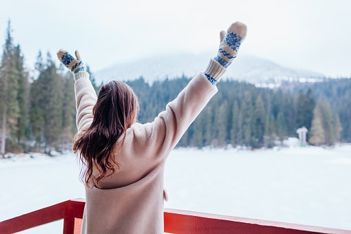 Woman stretching her arms looking at the snowy wilderness.