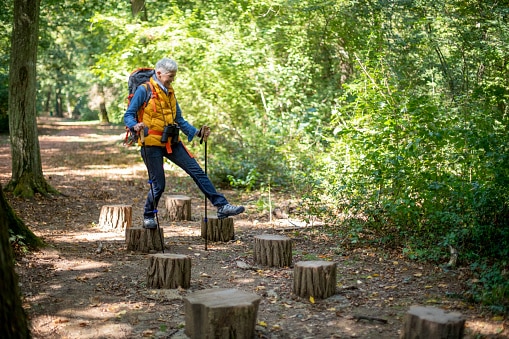 Senior woman balancing on tree stumps on her hike.