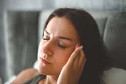 Woman with tinnitus rubbing her temple.