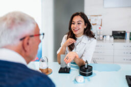 Audiologist is presenting a hearing aid device to a senior patient during a consultation in a modern audiology clinic, discussing options for improving hearing health
