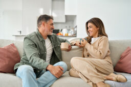 Happy couple talking relaxing on couch at home.